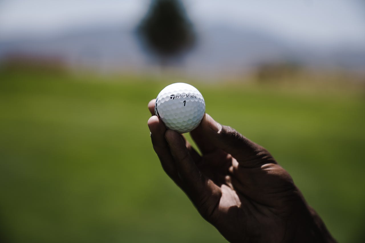 Detailed shot of a person holding a golf ball on a sunny day, perfect for sports themes.